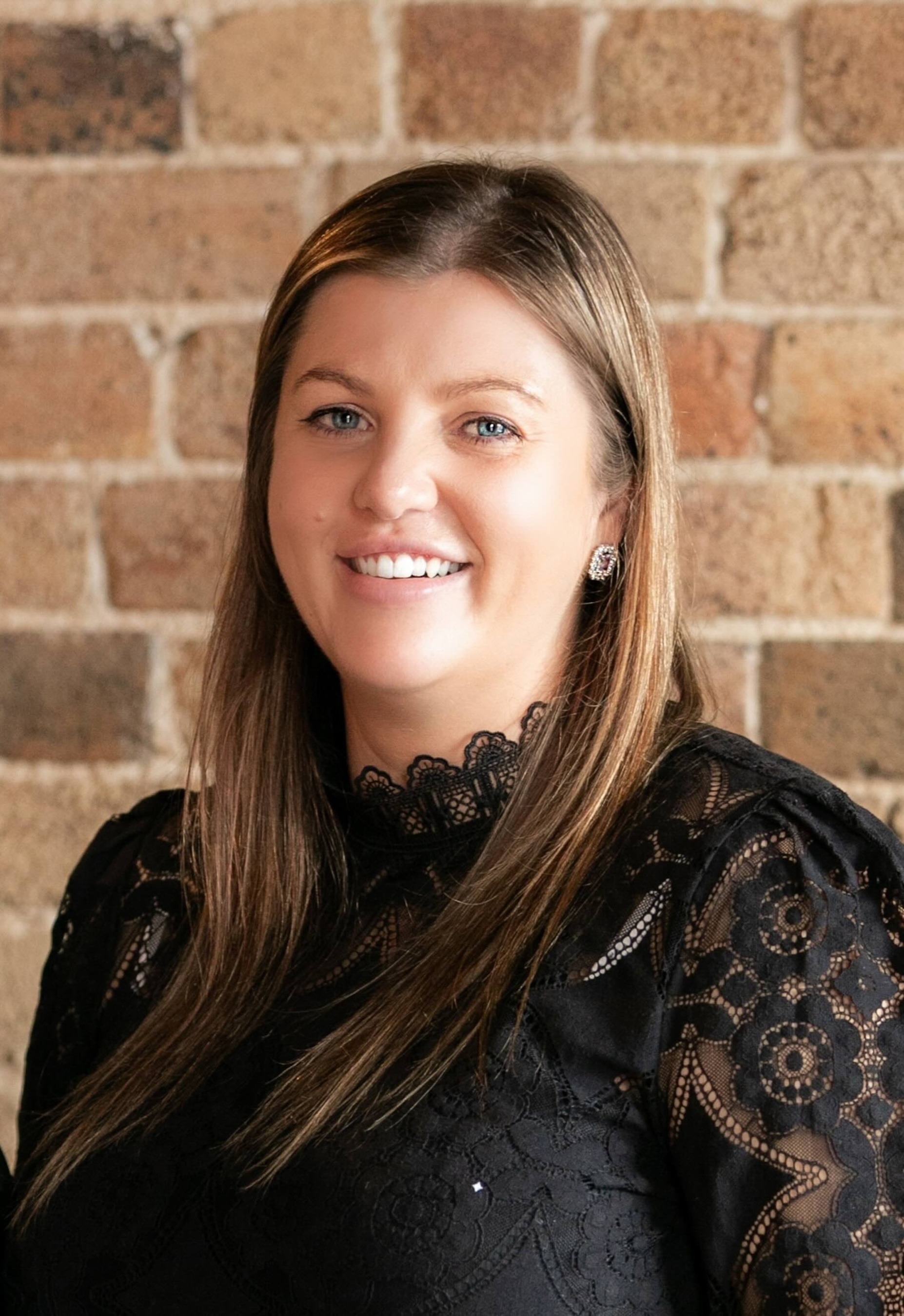 A headshot of Jade, the owner of Roast and Roam, she has long brown hair, blue eyes and is smiling.